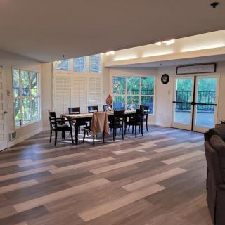 A spacious dining area with a wood floor and large windows offering natural light.