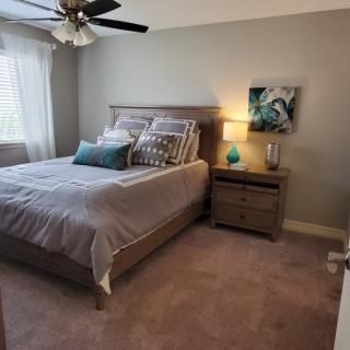 A cozy bedroom with a neatly made bed, nightstand, and soft lighting.