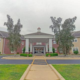 An exterior view of a building entrance with trees and a walkway.