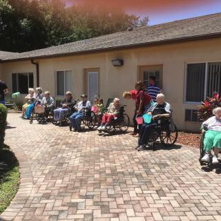 A group of elderly individuals sitting in wheelchairs outside on a sunny day.