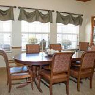 A well-furnished dining room with a table and chairs near windows.