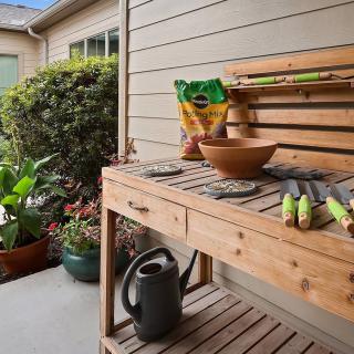 A well-organized potting bench with gardening tools, soil, and potted plants ready for use.