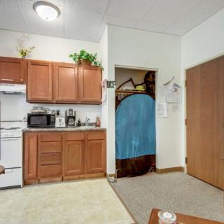 A cozy kitchen area with wooden cabinets, various appliances, and a decorative plant on display.