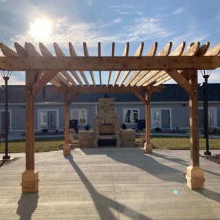 A sunlit wooden pergola in an outdoor courtyard setting.
