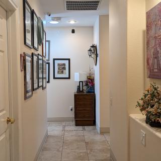 A well-decorated hallway featuring framed pictures and a small cabinet with decorative items.