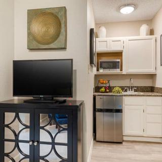 A cozy apartment kitchen with a TV and modern cabinetry.