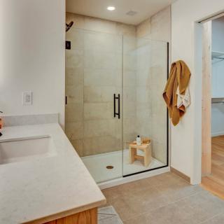 A modern bathroom with a glass-enclosed shower and a neatly organized vanity area.