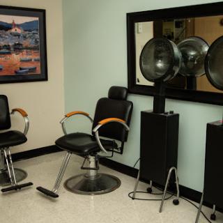 A glimpse into a contemporary beauty salon featuring barber chairs, hair dryers, and a large mirror.