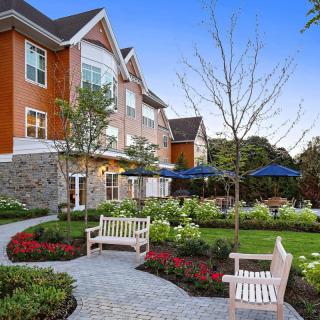 A beautifully landscaped garden with benches and a pathway in front of a residential building.