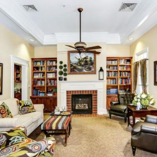A cozy living room with bookshelves flanking a central fireplace, featuring comfortable seating and a ceiling fan.