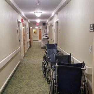 A quiet hallway in a healthcare facility with wheelchairs positioned along the side.