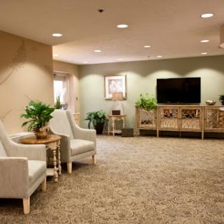 A spacious and inviting lobby area featuring comfortable seating, decorative plants, and a television.