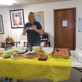 A community event featuring a spread of delicious homemade dishes, with a volunteer ready to serve.
