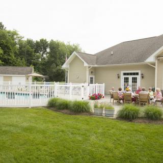 A backyard with a patio area, garden, and fenced swimming pool.