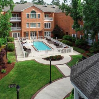 Aerial view of a residential apartment complex with a swimming pool surrounded by landscaped greenery.