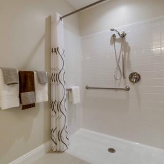 A modern bathroom shower area with a patterned curtain and neatly hung towels.