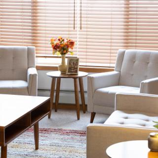 A cozy living room with comfortable chairs and a coffee table, adorned with a vase of flowers.