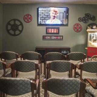 A cozy home theater with rows of chairs, a television screen, and film-themed decor.