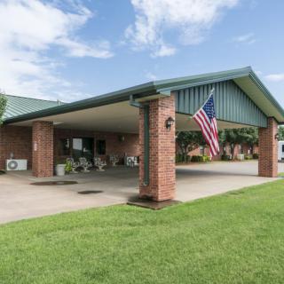 A brick building with a covered driveway and an American flag on display, surrounded by a well-maintained lawn.