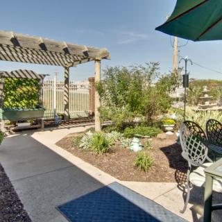 A beautifully landscaped garden with a pergola and outdoor seating on a sunny day.