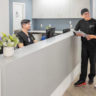 A healthcare professional interacting with the reception staff in a modern medical office.