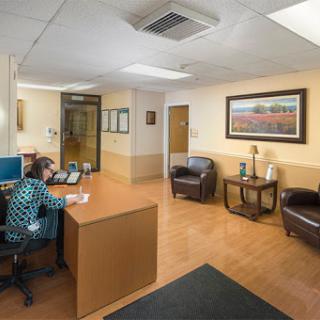 A modern reception area in a healthcare facility, featuring a desk, seating, and artwork.