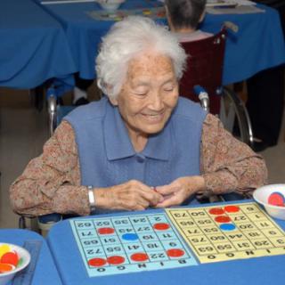 An elderly woman enjoying a game of bingo indoors.