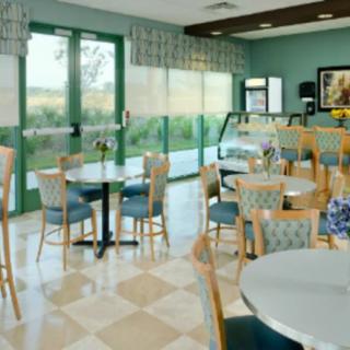 An empty cafe interior with tables and chairs, featuring large windows and tiled flooring.