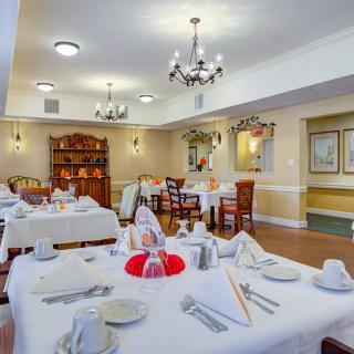 An elegant dining room set with tables and chairs, featuring chandeliers and sophisticated table settings.