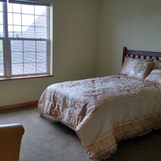 A cozy bedroom with a neatly made bed and large window.