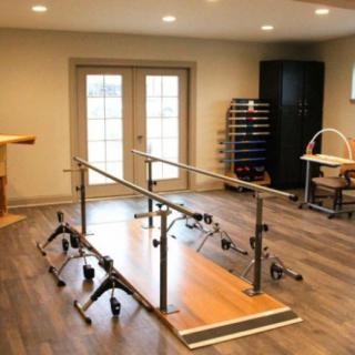 A well-equipped physical therapy room with parallel bars and rehabilitation equipment.