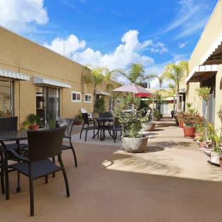 A sunny courtyard with tables, chairs, and plants under a blue sky.