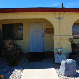 A cozy house entrance with desert landscaping and a cactus on the front porch.