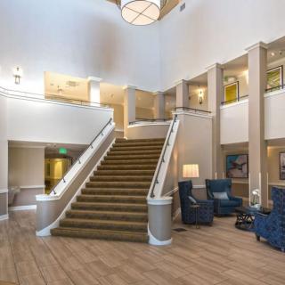A spacious hotel lobby featuring a grand staircase, comfortable seating, and elegant lighting.