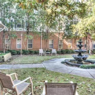 A peaceful courtyard with chairs and a fountain surrounded by trees.