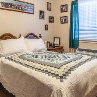 A cozy bedroom with a quilted bedspread and family photographs on the walls.