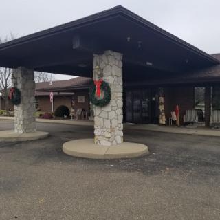 Entrance of a building decorated with holiday wreaths, set against a cloudy backdrop.