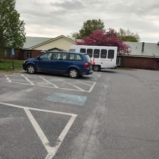 A blue car parked next to a white bus in a quiet parking lot.