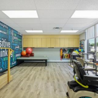 A well-equipped physical therapy room featuring exercise equipment and a motivational wall design.