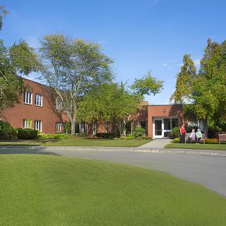 A brick building surrounded by trees and grass on a sunny day.