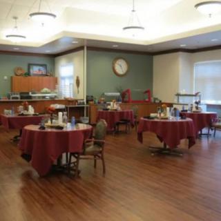 An empty dining room with round tables and chairs, set for service.