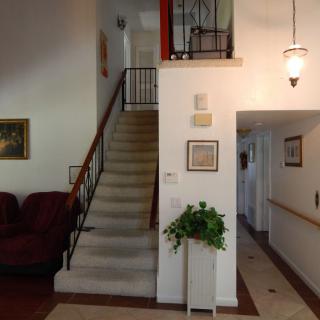 A cozy living room with a staircase leading to the upper floor, adorned with wall art and potted plants.