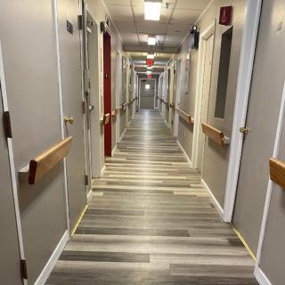 A long hallway with closed doors on either side, featuring modern flooring and muted wall colors.