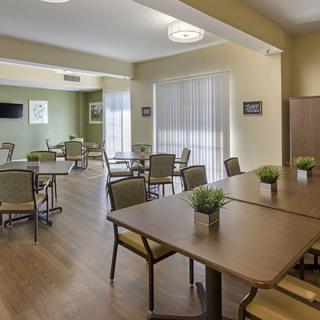 A modern dining area with neatly arranged tables and chairs, featuring decorative plants and ample natural light.
