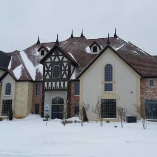 A large Tudor-style house surrounded by snow in a winter setting.