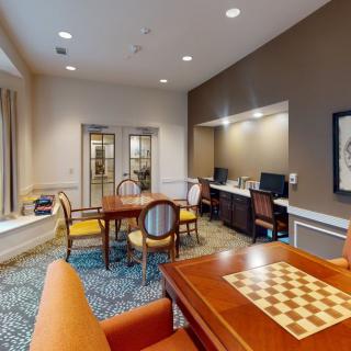 A cozy office space featuring a checkered board table, multiple chairs, and computer workstations.