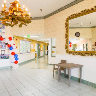 A bright hallway decorated for a celebration, featuring a chandelier and a large mirror.