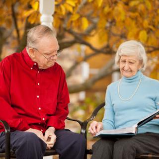 A couple enjoys reminiscing together while looking through a photo album on a beautiful autumn day.