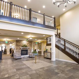 A welcoming lobby featuring a staircase, cozy seating areas, and a stylish chandelier.