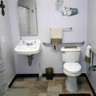 A neat and organized bathroom with wall-mounted sink, toilet, and decorative wall art.